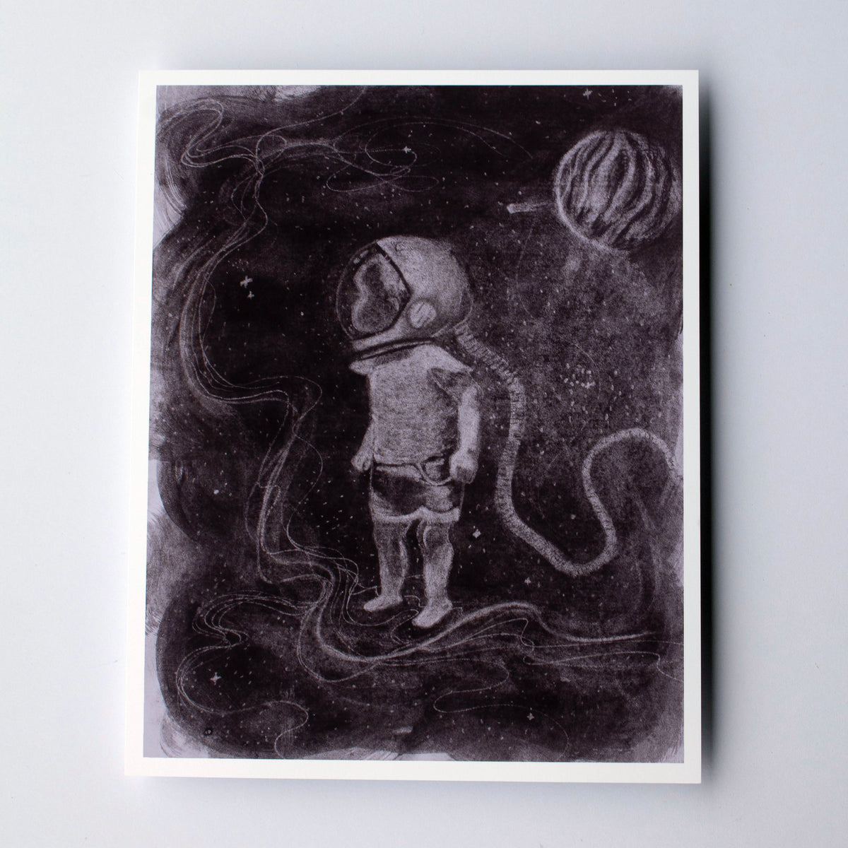 A square art print featuring a monochrome illustration of an astronaut standing in a dark space scene with a planet, displayed on a light gray background.