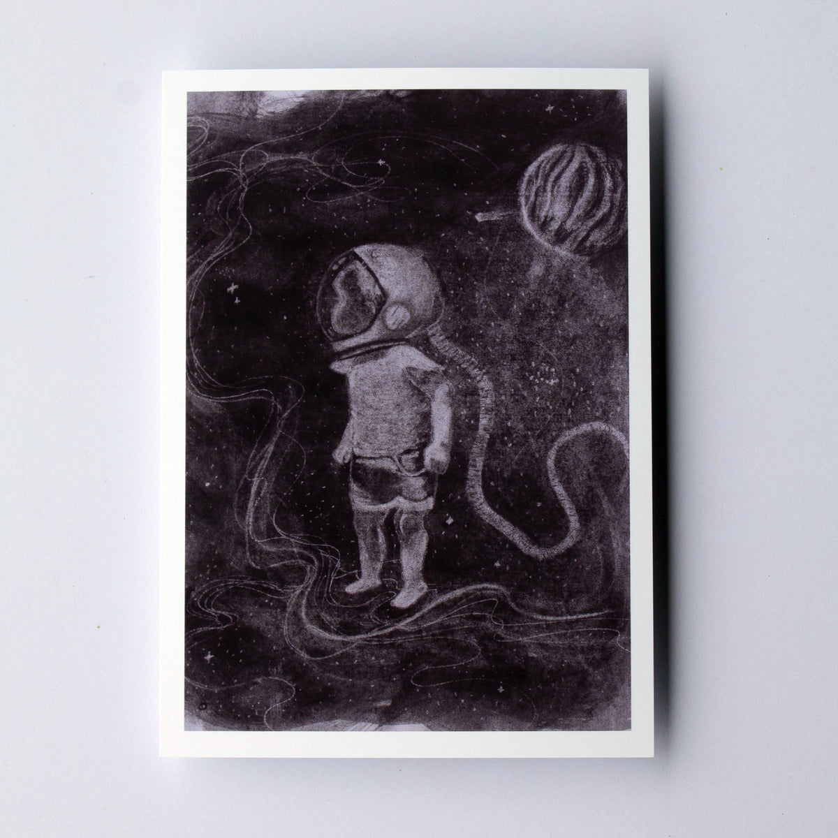 A square art print featuring a monochrome illustration of an astronaut standing in a dark space scene with a planet, displayed on a light gray background.