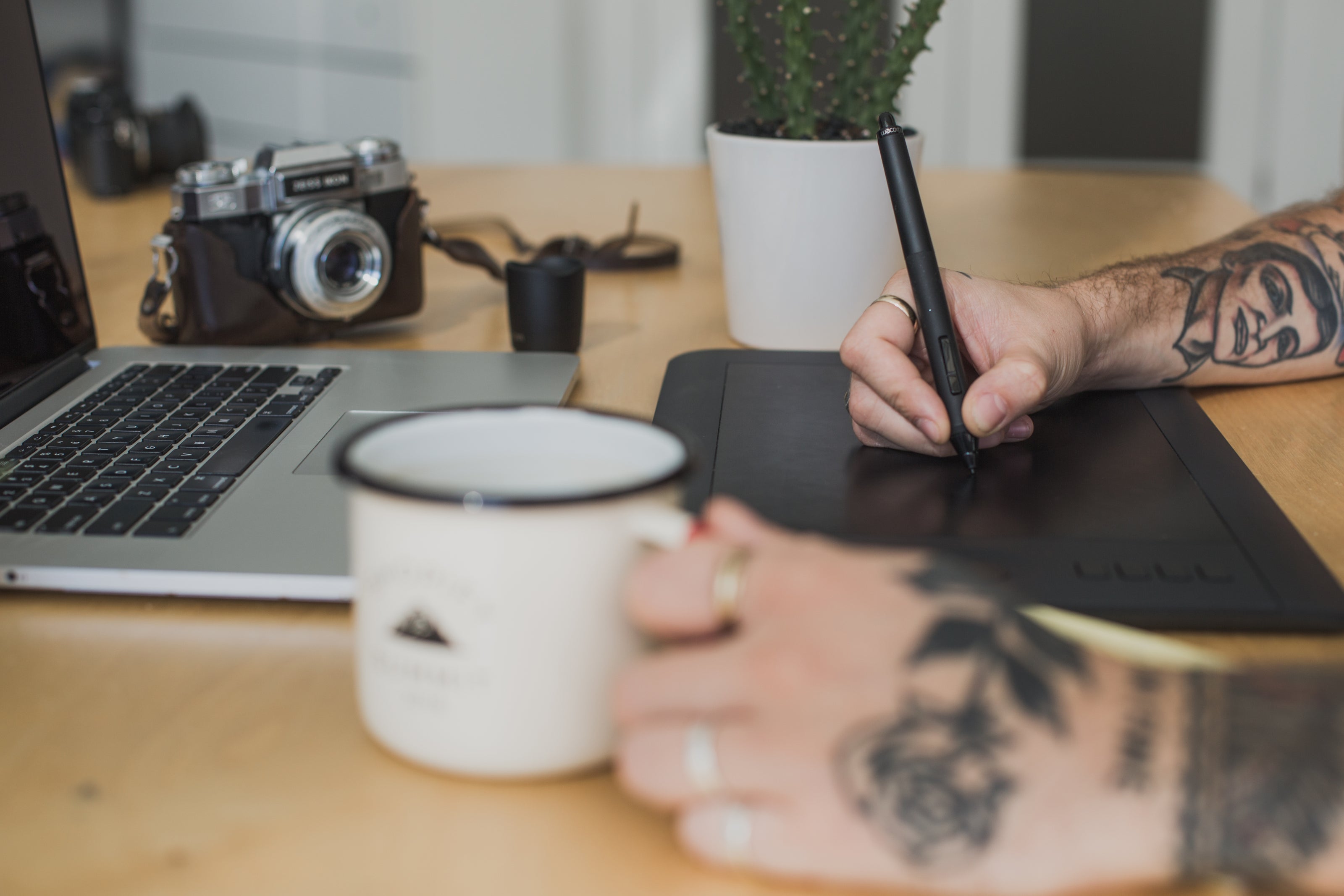 a photograph of an artist hands working with a cup of coffee in hand in a close up view.
