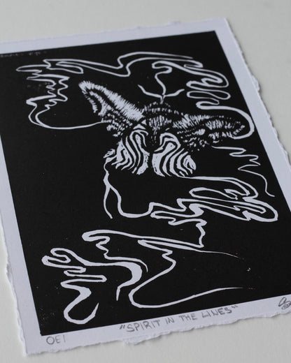 A black and white art print featuring an abstract, stylized moth with flowing line art, photographed on a light neutral background.