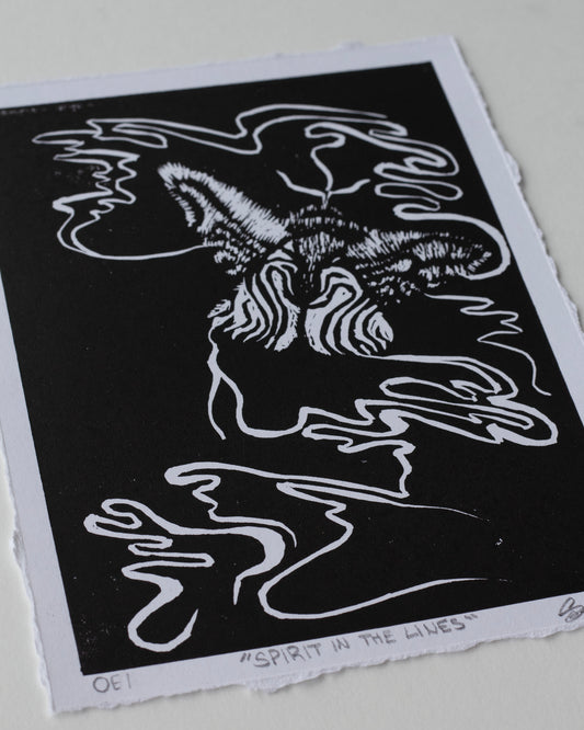 A black and white art print featuring an abstract, stylized moth with flowing line art, photographed on a light neutral background.